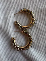 Aros dorados con dijes de aritos plateados.