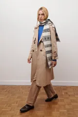 Trench coat largo color beige con doble botonadura, cuello solapa, cinturón ajustable y puños con tiras.