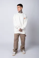 Buzo color crema de corte oversize confeccionado en tela friza con cuello redondo y puños y cintura acanalados. Presenta un pequeño bordado en el frente y un estampado grande en la espalda.