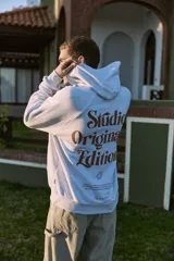 Canguro gris melange con capucha, mangas largas y estampado en la espalda con la inscripción "Studio Originals Edition" en color marrón.