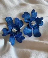 Par de aros con forma de flor color lila con centro de strass plateado.