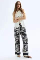 Pantalón de corte holgado con estampado de flores y hojas en azul y blanco. Modelo de tiro alto con elástico en la parte posterior de la cintura y cierre oculto con corchete en un lado. Bolsillos laterales discretos y piernas amplias con pliegues adelante y atrás.