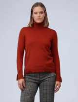 Polera de punto fino color óxido, de manga larga con pequeños tajos en los puños y cuello alto.