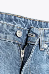 Pantalón de jean celeste de corte recto y tiro bajo, con cinco bolsillos y cierre frontal con cremallera y botón metálico.