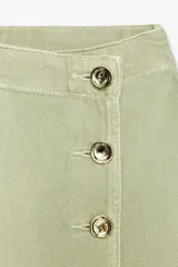 Falda pantalón corta color crudo, de tiro alto con delantero cruzado y cierre con cremallera oculta y botones.