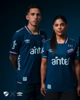 Camiseta de fútbol Umbro del Club Nacional de Football, modelo Alternativa. Diseño azul con detalles en blanco y rojo en cuello y mangas. Incluye logo de Umbro, escudo del club y sponsor Antel en el frente.