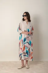 Vestido largo de lino color verde militar con estampado de hojas en tonos azul, naranja y marrón. Tiene cuello mao con botones, mangas tres cuartos y un bolsillo en el pecho.
