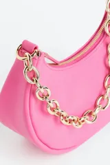 Cartera de hombro chica color rosa con correa de cadena gruesa de metal dorada y cierre.