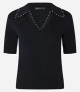 Blusa de punto negra con cuello polo, escote en V y mangas cortas. Detalle de mini perlas aplicadas en el cuello.