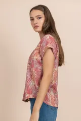Camisa de manga corta color coral con estampado de hojas de palmera en tonos blanco y amarillo.