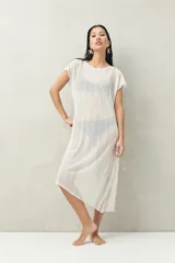 Top largo color blanco, confeccionado en tejido liviano con transparencia y caída fluida.