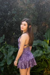 Vestido corto negro con estampado de hojas doradas, escote en V, breteles finos cruzados en la espalda, cut-outs laterales bajo el busto y volado en el ruedo.