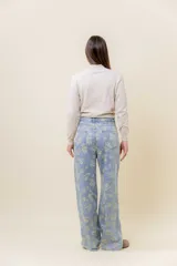 Pantalón de jean de tiro medio-alto, pierna ancha y lavado celeste claro, con estampado floral en tono amarillo pálido.