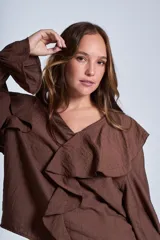 Blusa negra de manga larga con escote en V y volados en el frente y puños elásticos.