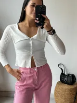 Remera negra de tejido de punto acanalado, con cuello polo, cierre frontal con botones y mangas largas.