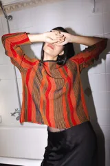 Buzo tejido con lurex, con rayas verticales en tonos naranja, rojo y marrón.