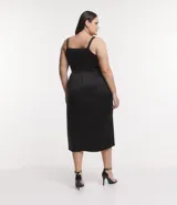 Vestido midi de tela satinada color negro, con escote drapeado, breteles medianos, cintura ajustada y pollera cruzada.