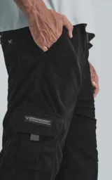 Pantalón negro de pana con corte ancho, cintura elástica y bolsillos cargo.