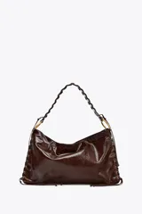 Bolso de hombro alargado color marrón oscuro, con detalle de pasados metálicos en los laterales y asa trenzada. Doble bolsillo interior con cremallera. Cierre mediante botón imantado.