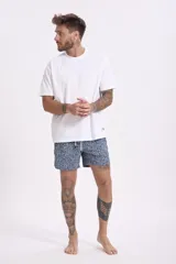 Short de baño para hombre, color azul oscuro con estampado floral o botánico en tonos rosados y celestes. Presenta cordón de ajuste blanco en la cintura.