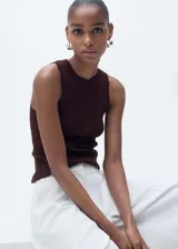 Musculosa blanca de tejido de punto fino, cuello redondo, tirantes anchos y diseño entallado.