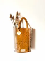 Bolso matero de cuero color marrón con textura croco y detalles en cuero color taupe. Tiene doble asa corta de cuero y un dije colgante en forma de cruz.