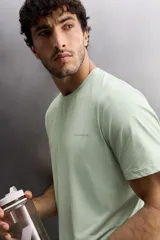 Camiseta deportiva verde claro confeccionada en tejido técnico, ligero y elástico en cuatro direcciones. Tiene cuello redondo, manga corta, zonas con estructura perforada y logo estampado.