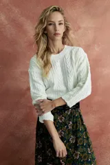Sweater de punto trenzado color crudo, con cuello redondo y mangas largas.