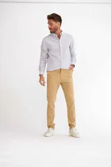 Pantalón de vestir color beige, de corte recto, con bolsillos laterales y traseros. Se ajusta a la cintura con cinturón de cuero marrón.