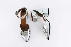 Zapato de cuero color dorado con punta fina, taco cuadrado y pulsera con hebilla y ojales.