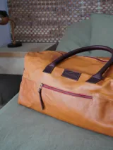 Bolso de viaje tipo weekender de cuero color marrón, con doble asa corta y correa larga desmontable. Cuenta con cierre superior, bolsillos internos y externos con cierre metálico. Forro interior de tela. Marca Sierra Mora.