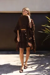 Ruana marrón tejida en lana merino con detalles de lino y flecos.