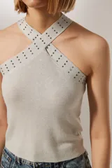 Top cropped gris metalizado con cuello halter y detalle de studs.