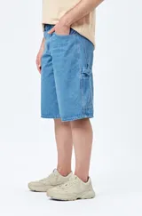 Bermuda carpenter de denim negro, corte relajado y largo a la rodilla, con costuras visibles y múltiples bolsillos funcionales.