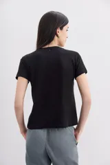 Remera negra de algodón con calce relajado, cuello redondo y mangas cortas. Presenta bordados florales con lentejuelas en el frente.