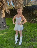 Conjunto de encaje blanco compuesto por un top con tirantes finos y una minifalda con short incorporado.