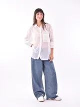 Camisa blanca traslúcida con rayas verticales doradas, de corte holgado, manga 3/4 y bolsillo en el pecho.