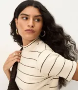 Blusa de ribana color beige con rayas horizontales negras, cuello medio y mangas cortas.