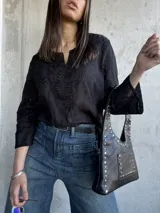 Blusa negra con bordado tipo broderie, escote en V y mangas 3/4.