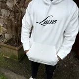Buzo hoodie negro de corte oversize, con capucha, bolsillo frontal y estampa blanca en la espalda con la leyenda "Luxe" y "The Luxe Vip Club".