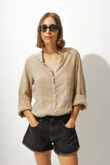 Camisa color beige de lino con cuello mao y mangas 3/4 con botón para sujetar.