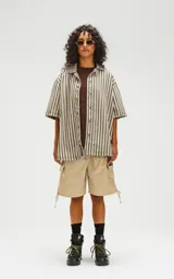 Camisa oversize de manga corta con cuello abierto y estampado a rayas verticales en tonos verde y beige.