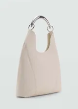 Bolso tipo hobo color crema, con asa rígida plateada y costuras laterales a la vista.