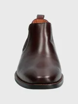 Bota Chelsea de cuero color vino (bordó oscuro) con puntera cuadrada y elástico lateral negro. Posee suela negra con costura de vira visible en color marrón claro.