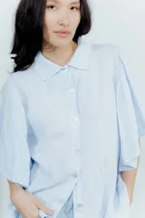 Camisa blanca de lino con cuello clásico y mangas cortas amplias.