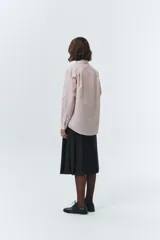 Camisa de algodón y nylon, color rosa pálido con finas rayas verticales blancas. Presenta un cuello clásico, botones frontales y un calce oversized.