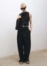 Chaleco negro con cierre de botones en la parte delantera, cuello de pico, sin mangas y dos bolsillos de ribete en la parte delantera.