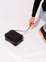 Bandolera clásica color beige, confeccionada en cuero natural, con diseño acolchado en forma de rombos. Posee correa de cadena entrelazada con cuero y cierre principal.