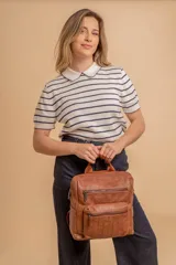 Mochila mediana color marrón de símil cuero con asa superior, dos compartimientos con cierre y bolsillos frontales.