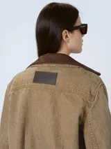Chaqueta de denim azul oscuro con cuello de piel sintética color borgoña, cierre frontal con botones a presión, bolsillos de parche con solapa en el pecho y bolsillos laterales.